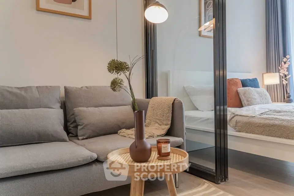 Modern living room with cozy sofa and stylish decor adjacent to a bedroom with glass partition.