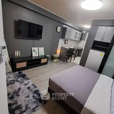Modern studio apartment with sleek design, featuring a cozy bed, stylish kitchen, and wall-mounted TV.