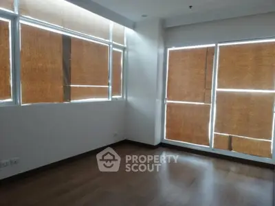 Spacious empty room with large windows and wooden flooring, perfect for customization.