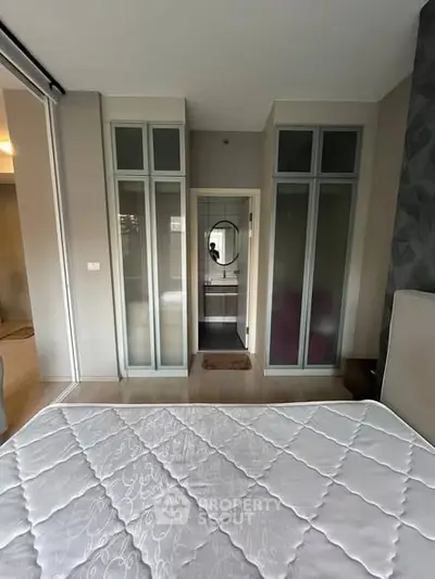 Modern bedroom with stylish frosted glass wardrobes and a cozy bed setup.
