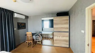 Modern bedroom with wooden flooring, mirrored wardrobe, and study desk in a stylish apartment.
