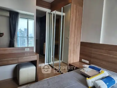 Modern bedroom with wooden accents and mirrored closet doors in a high-rise apartment with city view.