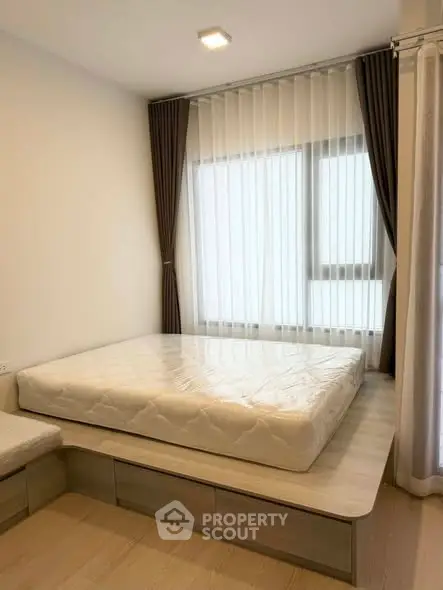 Modern bedroom with platform bed and large window, featuring elegant curtains and natural light.