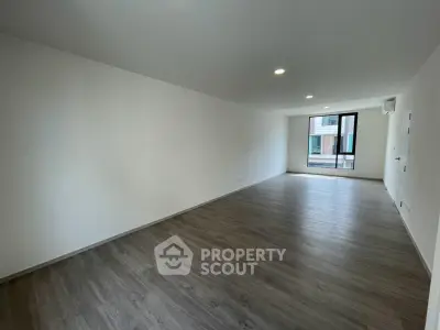 Spacious empty living room with wooden flooring and large window