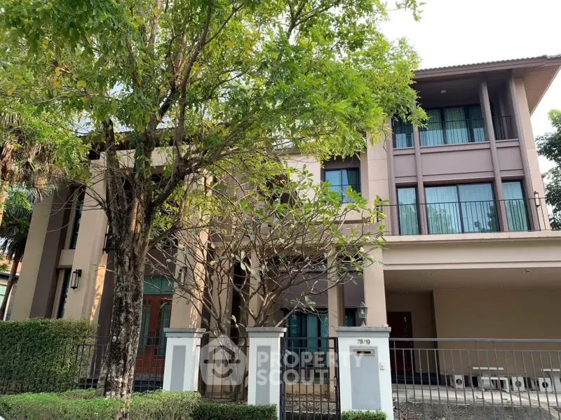 Elegant modern house with lush greenery and spacious balcony, perfect for luxury living.