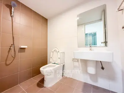 Modern bathroom with sleek fixtures and neutral tiles, featuring a wall-mounted shower and contemporary sink.