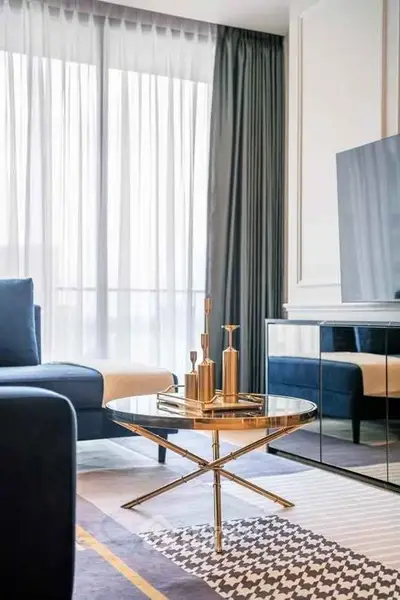 Elegant living room with modern decor, featuring a sleek glass coffee table and luxurious blue sofa.