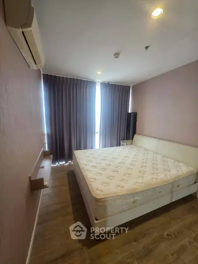 Cozy bedroom with large window and modern furnishings in a stylish apartment.