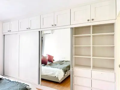 Spacious bedroom with built-in wardrobe and mirrored sliding doors, showcasing modern design and ample storage.