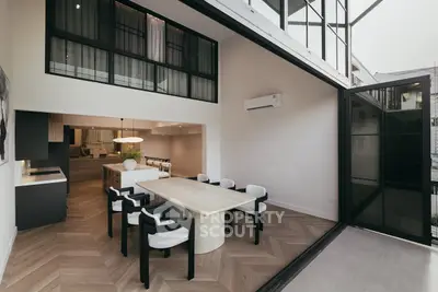 Modern open-plan living and dining area with stylish furniture and large windows.