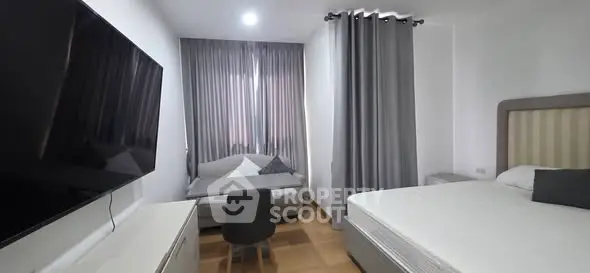 Modern bedroom with sleek TV and cozy seating area, perfect for relaxation.