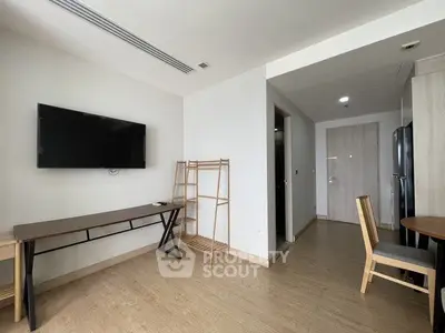 Modern apartment interior with wooden flooring, wall-mounted TV, and minimalist furniture.