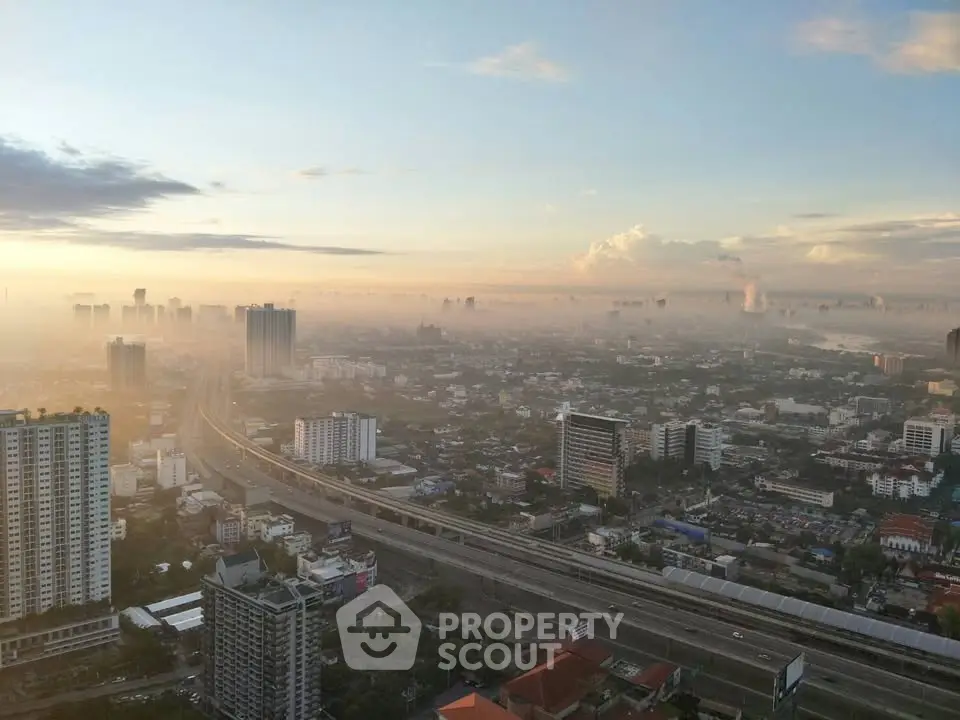 Stunning cityscape view from high-rise building at sunrise, showcasing urban skyline and highway.