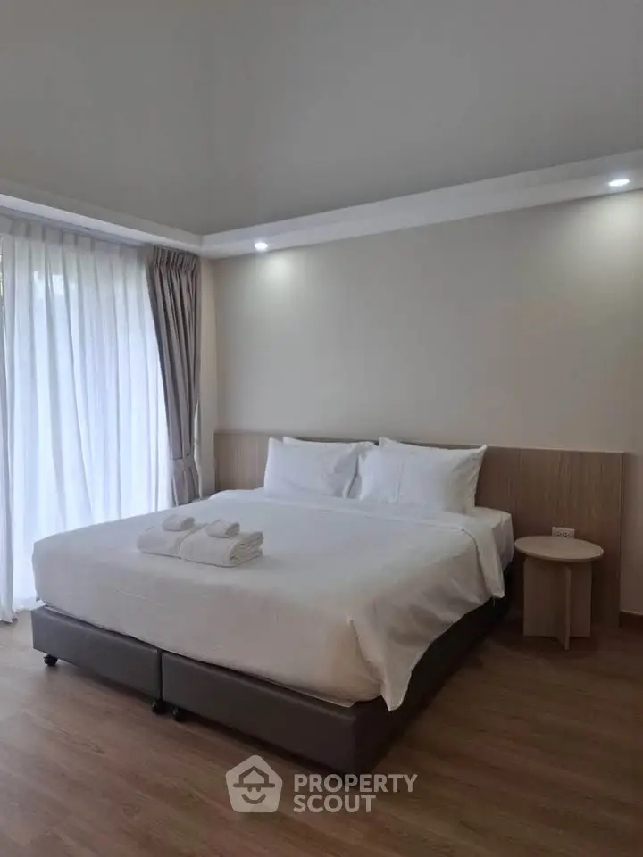 Spacious bedroom with modern decor and natural light from large windows.