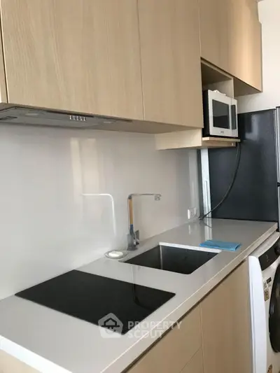 Modern kitchen with sleek cabinetry, induction cooktop, and integrated appliances in a stylish apartment.
