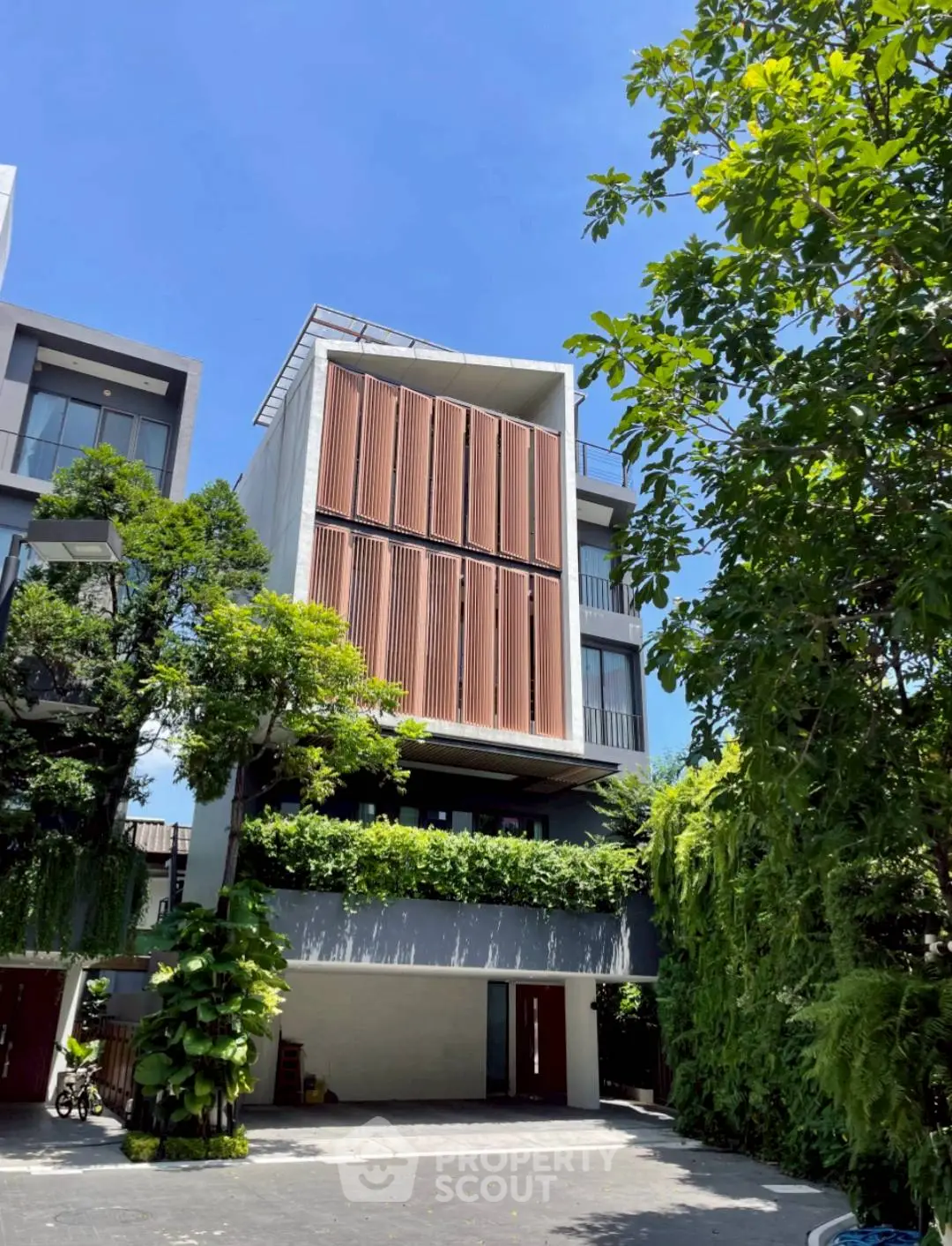 Modern architectural townhouse with lush greenery and sleek design in urban setting.