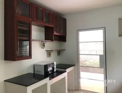 Modern kitchen with sleek cabinetry and microwave, featuring a bright door leading to outdoor space.