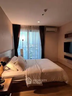 Cozy bedroom with large window and modern furnishings in a stylish apartment.