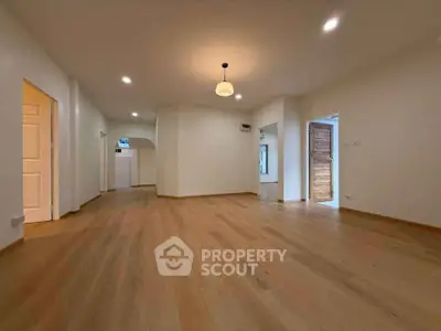 Spacious open-plan living area with elegant wooden flooring and modern lighting.
