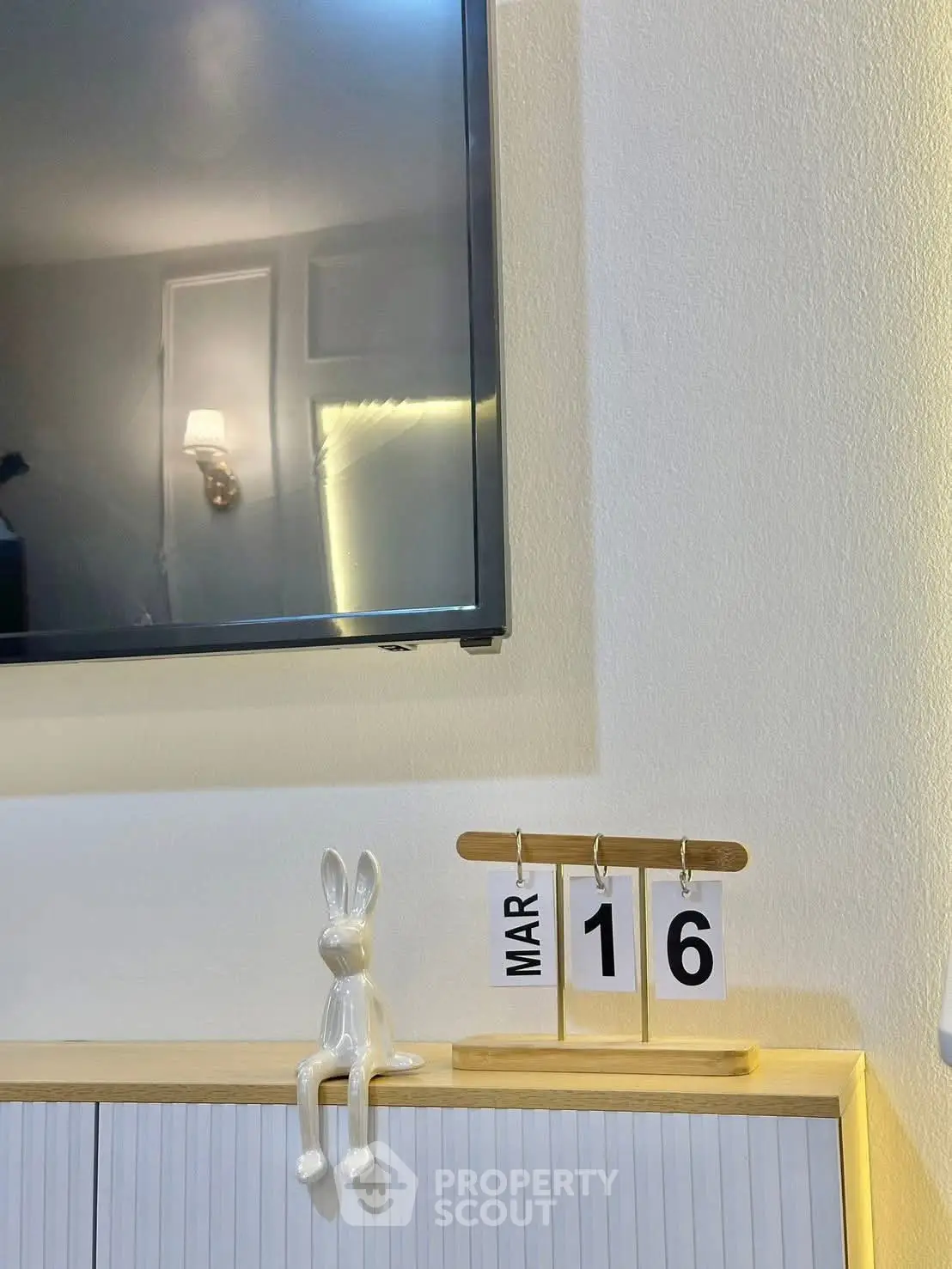 Modern interior with wall-mounted TV and decorative calendar on cabinet