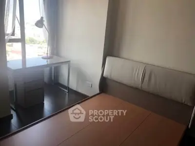 Cozy bedroom with desk and large window offering natural light and city view.