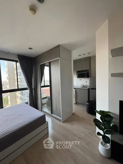 Modern apartment interior with bedroom and kitchen, featuring large windows and stylish decor.