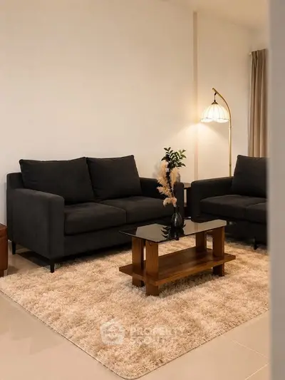 Stylish living room with modern dark sofas, elegant floor lamp, and chic coffee table on plush rug.