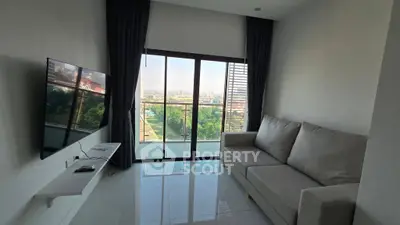 Modern living room with large window and city view, featuring sleek furniture and a wall-mounted TV.