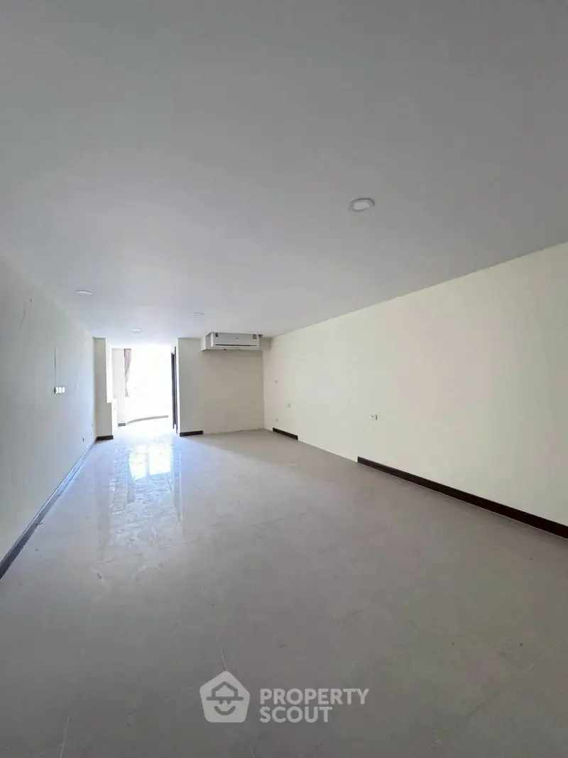 Spacious empty room with bright natural light and air conditioning, ideal for customization.