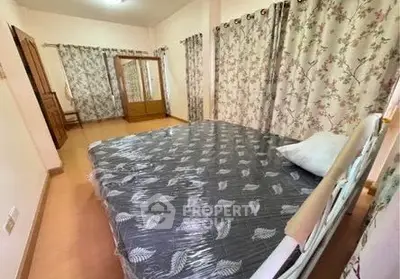 Spacious bedroom with floral curtains and wooden wardrobe