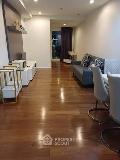Spacious modern living room with wooden flooring and stylish furniture in a cozy apartment.