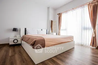 Spacious bedroom with elegant decor and large window for natural light
