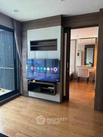 Modern living room with wooden flooring and sliding door to bedroom