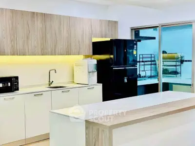 Modern kitchen with sleek cabinetry, island, and black appliances in a bright, open layout.
