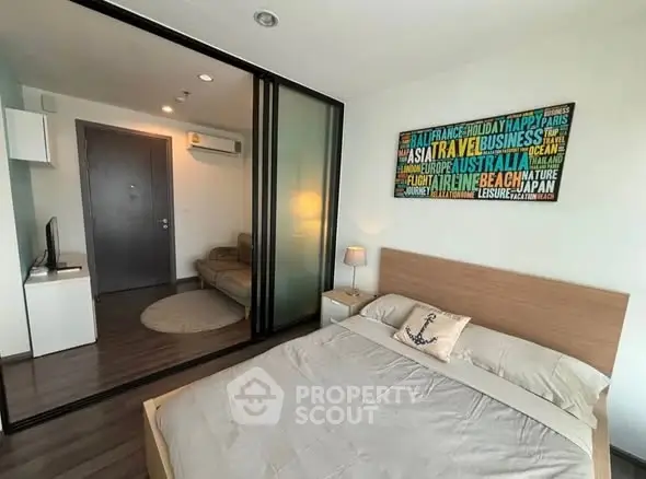 Modern bedroom with sliding glass doors and cozy living area in stylish apartment.