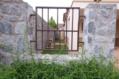 Charming stone wall with iron gate leading to a cozy backyard garden in a suburban home.