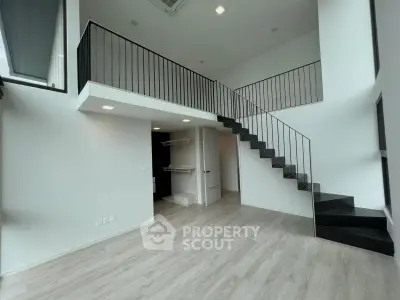 Modern duplex apartment with sleek staircase and open layout, featuring high ceilings and abundant natural light.