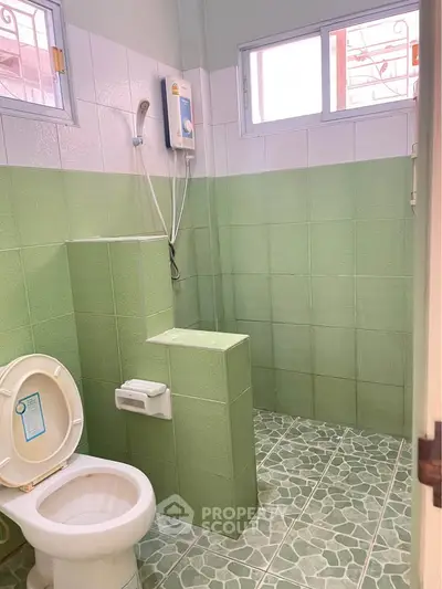 Charming green-tiled bathroom with modern fixtures and natural light