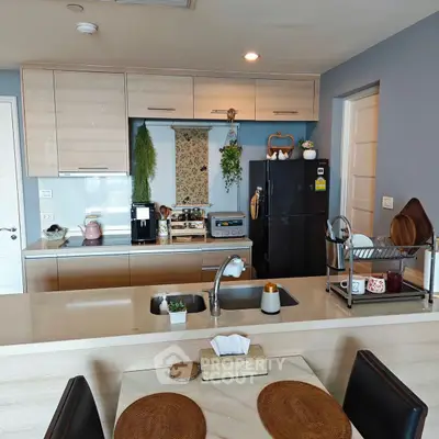 Modern kitchen with sleek cabinetry, appliances, and dining area in stylish apartment.