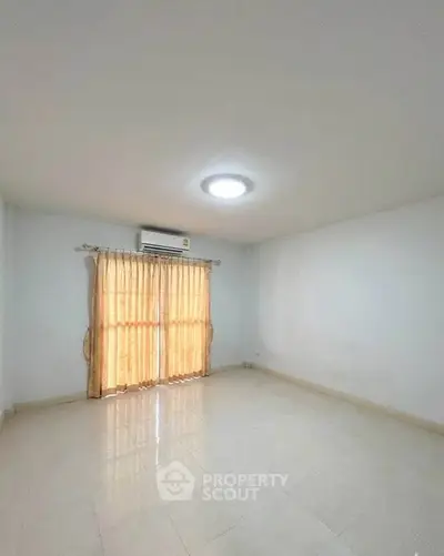 Spacious empty room with tiled floor and large window, perfect for customization.
