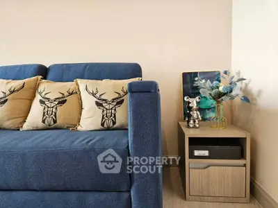Stylish living room with blue sofa and decorative pillows, modern side table with floral arrangement.