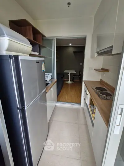 Modern compact kitchen with sleek appliances and open layout leading to cozy living area.
