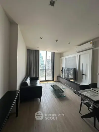 Modern living room with sleek furniture and city view balcony in high-rise apartment.