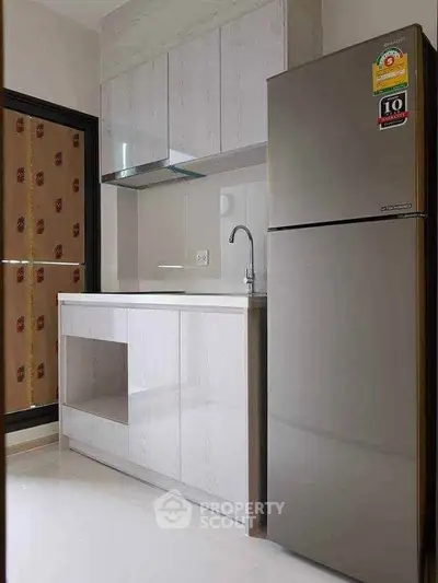 Modern kitchen with sleek cabinetry and stainless steel fridge in a compact layout.