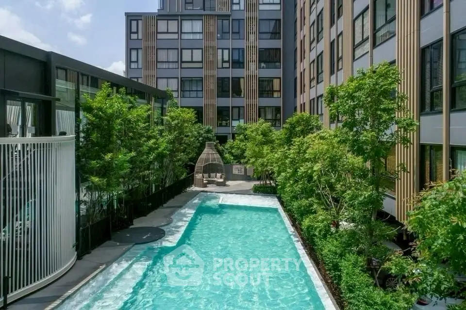 Modern apartment building with a refreshing outdoor pool and lush greenery.