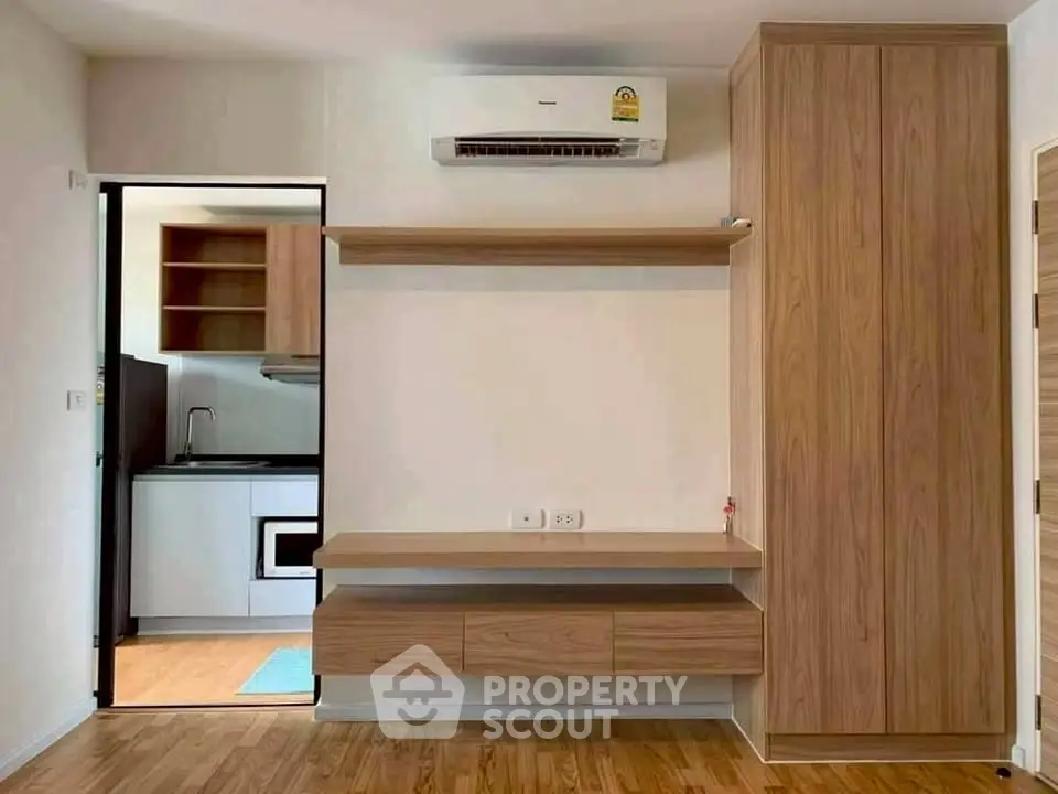 Modern apartment interior with wooden cabinetry and compact kitchen area.