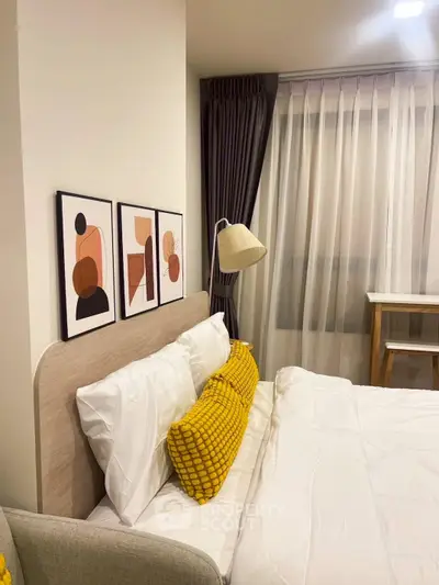 Cozy bedroom with modern decor and stylish artwork, featuring plush pillows and ambient lighting.