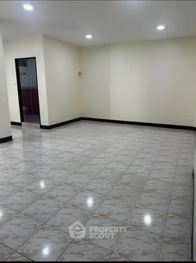 Spacious empty room with tiled flooring and recessed lighting, ideal for customization.
