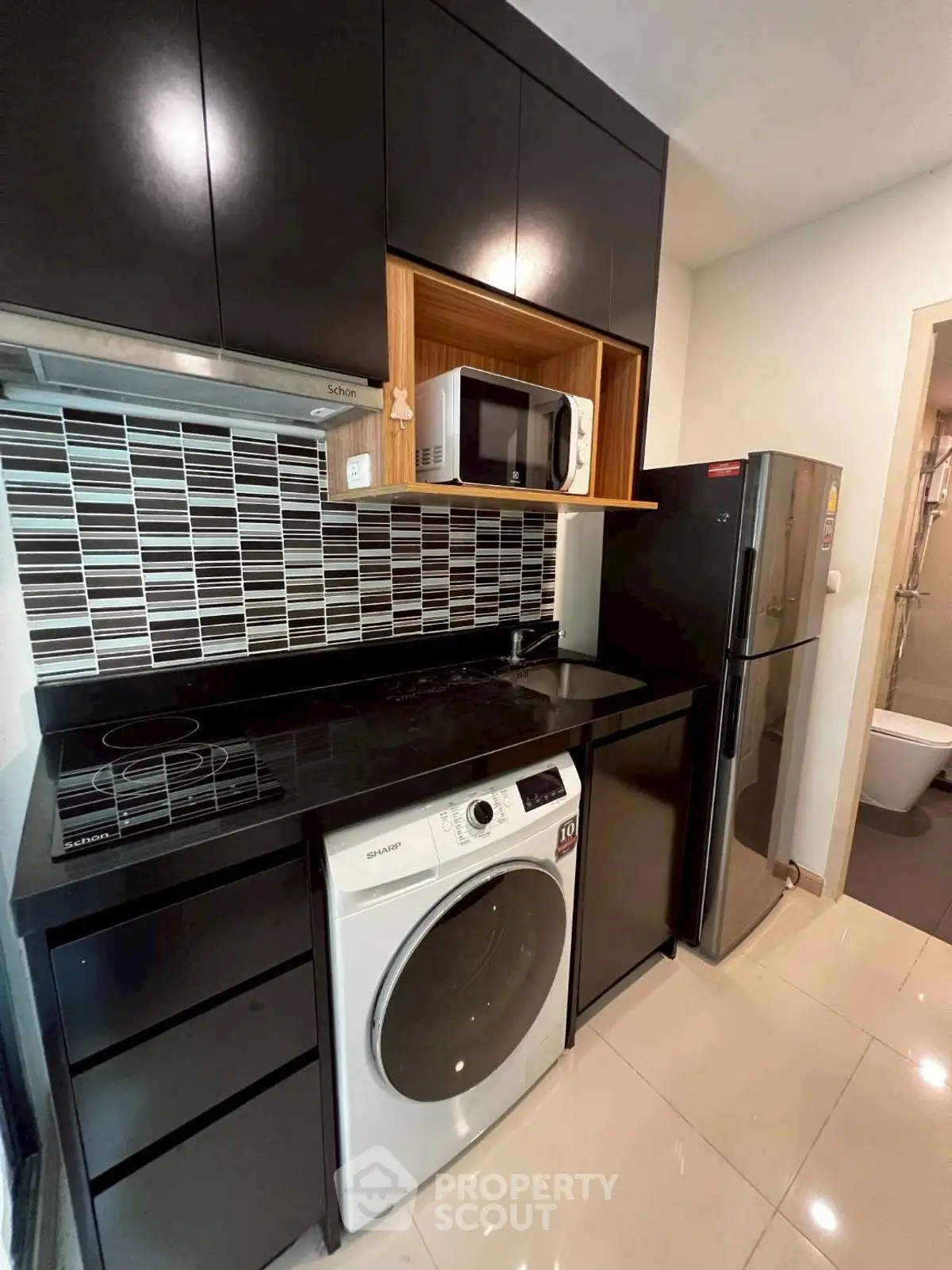 Modern kitchen with sleek black cabinets, built-in appliances, and stylish backsplash.