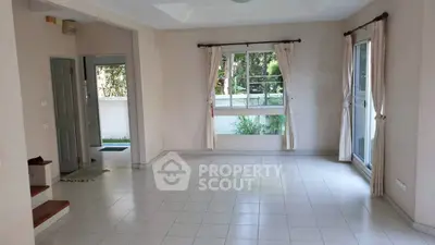 Spacious living room with large windows and garden view, perfect for natural light lovers.